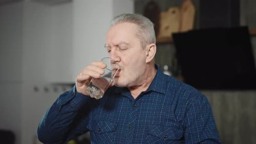 Older Man Taking Pill with Water at Home