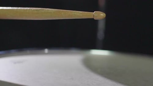 Super close up slow motion of a drum stick hitting a snare drum multiple times and bouncing off the