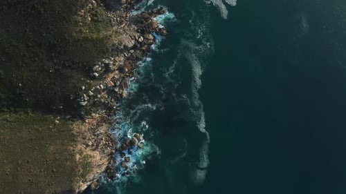 Aerial Drone Top Down of Ocean Waves Crashing against Rocks. Seascape Coastline at Sunset in Cape To