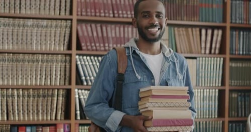 Slow Motion Portrait of Happy African American Person Standing in College Library Holding Books