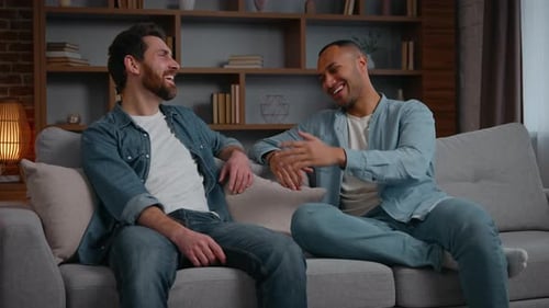Two men sitting on couch and talking, laughing