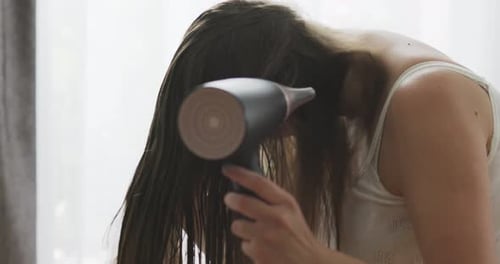 Woman Dries Her Long Brunette Hair With Hairdryer