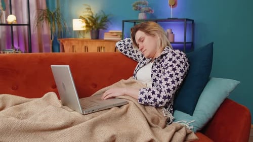 Relaxed Young Adult Using Laptop on Tangerine Couch