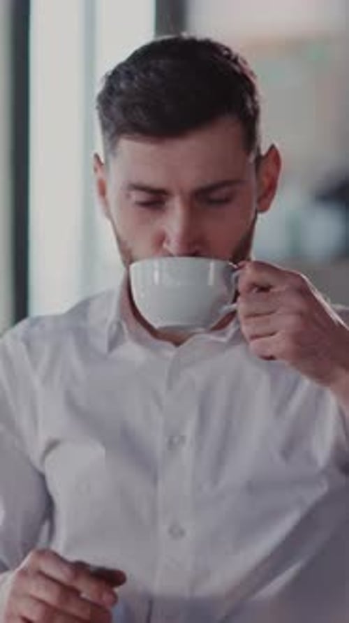 Man Enjoys Coffee Break at Desk