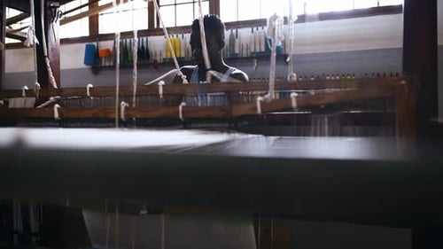 Man, floor treadle loom and thread production at clothing factory, manufacturing and craftsmanship