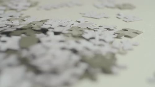 Pièces de puzzle blanches et grises posées au hasard sur une surface blanche avec un fond sombre. Dos lisse