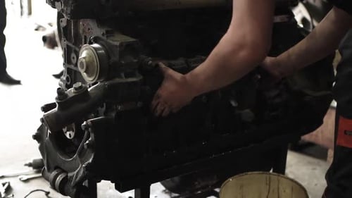 Mechanic Repairing Large Dirty Engine in Workplace