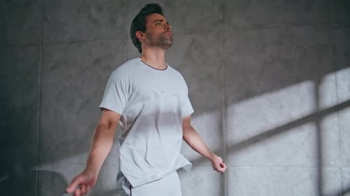 Man Jumps Rope in Room with Concrete Wall