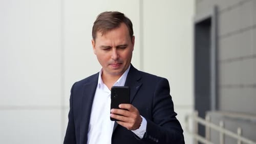 Selbstbewusster Geschäftsmann im Anzug schreibt Nachricht am Telefon