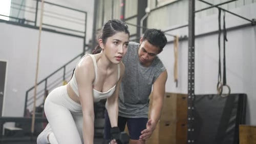Pretty woman and instructor are exercising at a fitness center.