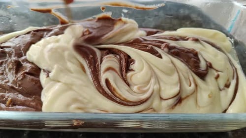 The cake batter in the cake mold is mixed with a toothpick, to make a cake