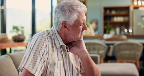 Senior Man Massaging Neck at Home with Pain