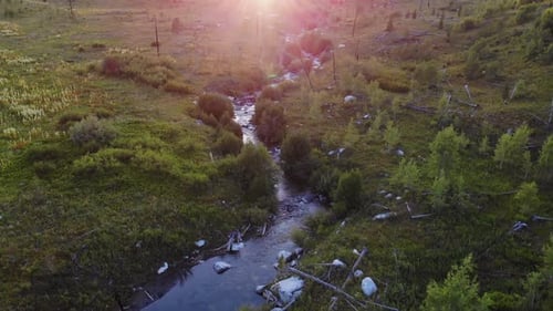 Aerial low shot over the course of a river in the Grand Teton Park with sun beams in the top of the