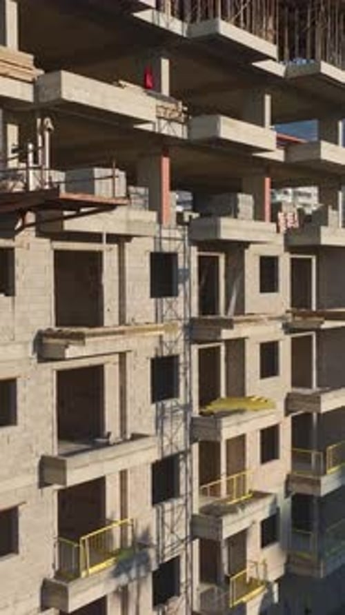 Vertical Video of Workers Pouring Concrete and Building Walls While a Crane Assists With Material
