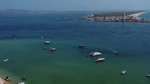 Water canal between Lighthouse island and Deserted Island with tour boats on emerald water, Algarve
