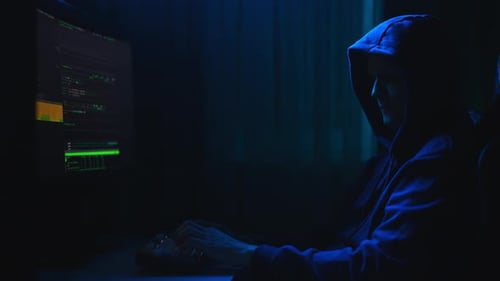 Side View of Dangerous Hacker Male Wearing Sweatshirt with Hood Breaking Into Company Data Servers