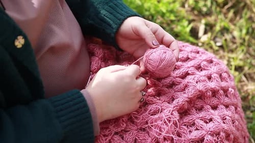 Woman Crafts Pink Knitted Blanket Outside