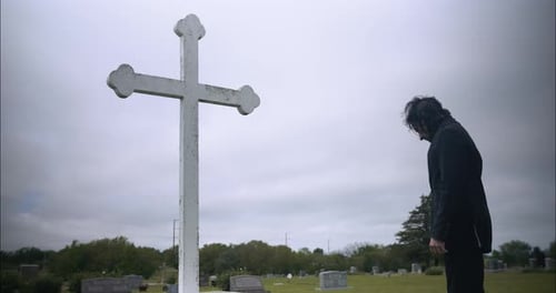 Junger Mann betet im Gottesdienst vor dem christlichen Kreuz
