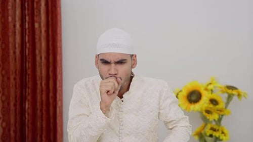 Man Coughing and Rubbing Sore Throat Indoors