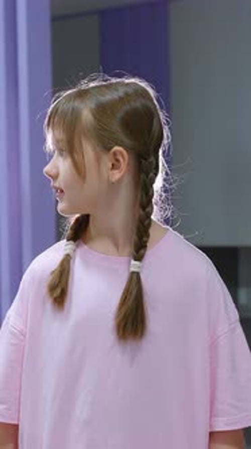 Attentive Young Girl in Pink Shirt Observing Something in Gym