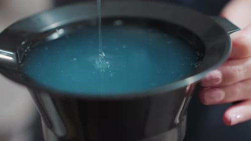 Gros plan d'un colorant soigneusement mélangé en salon, un styliste professionnel verse et mélange habilement