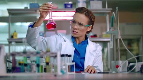 Woman scientist analyzes red liquid in laboratory