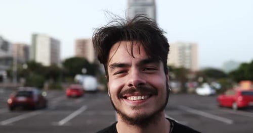 Young latin man smiling happily on a London street in the summer sun