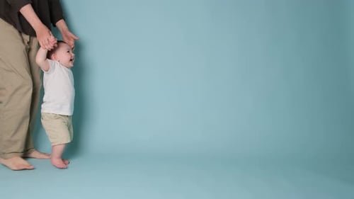 Happy toddler baby learns to walk and takes his first steps with the help mother