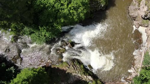 An aerial view shows water rushing over rocks and forming a stream Trees line the stream's edges