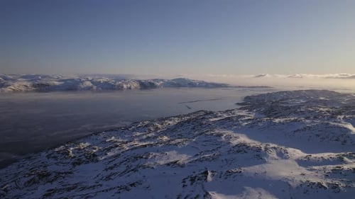 Luftaufnahme der schneebedeckten Berge mit Meer- und Horizontwolken