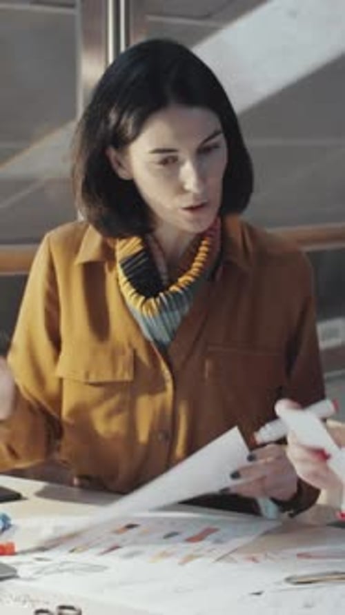Zwei Modedesigner wählen Skizzen aus, brünette Frau lächelt vor der Kamera