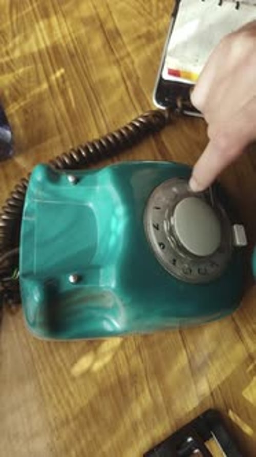 Finger dials number on rotary dial telephone before replacing handset