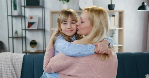 Blonde Woman and Girl Embrace Affectionately Indoors