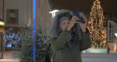 Woman Taking Cell Shots in the Street with Christmas Illumination