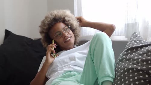 Woman on Phone While Lying on Couch Indoors