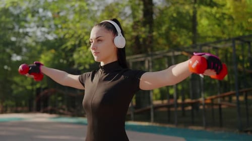 Woman Lifts Weights in Sunny Outdoor Park