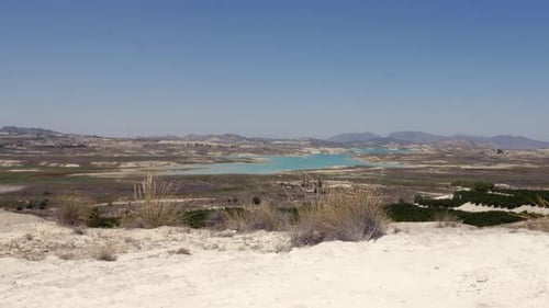 Blue salt lake in spin. The arid Spanish desert landscape has shrubs and sandy rocks