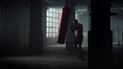 Angry Boxer Silhouette Punching Sports Bag In Dark Gym. Male Powerful Fighter Boxing Punchbag Glo...