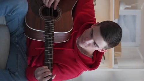 Young Adult Playing Acoustic Guitar in Home