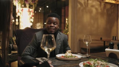 Des personnes diverses de races et d'ethnies différentes dînent ensemble dans un restaurant en train de serrer des verres