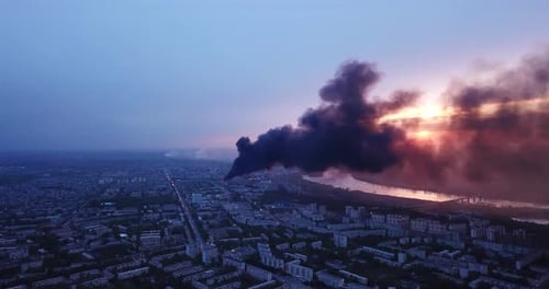 Black smoke rising over cityscape, drone view.