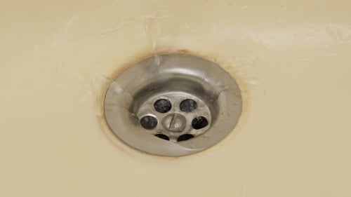 Water droplets falling into a stained sink, close-up, slow motion