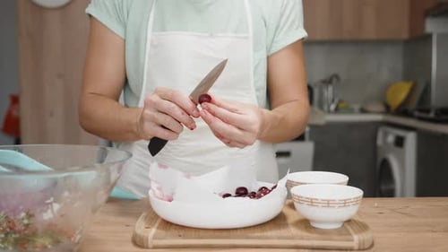 Young Adult Pitting Cherries in Kitchen for Recipe