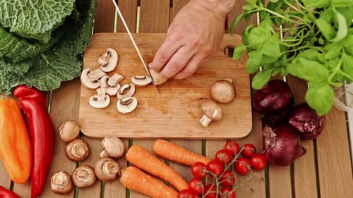 Chopping Fresh Mushrooms with Knife on Wood Cutting Board