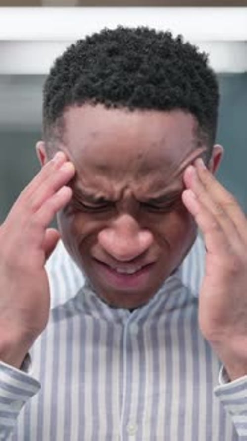 Young Man Massaging Temples Experiencing Headache Pain