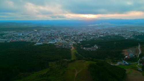 Aerial of the City and Big Green Hills Clip Summer Big City and Cloudy Sky During Sunset