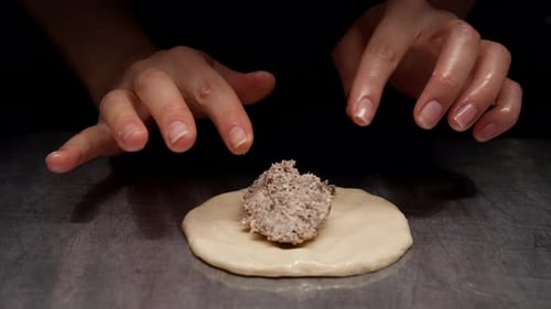 Closeup Sequence of Raw Dough Being Prepared with a Savory Meat Filling on a Dark Counter Surface