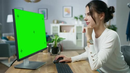 Beautiful Young Girl Works on a Green Mock-up Screen Personal Computer while Sitting at Her Desk in