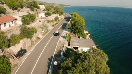 Car with Paddle Board on Roof Drives Along Coastal Road