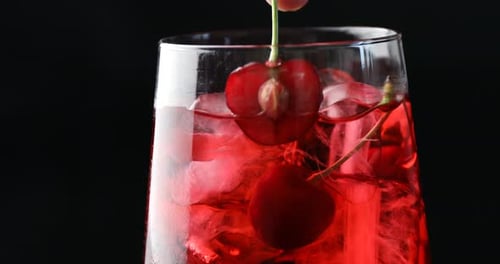 Refreshing cocktail with ice and cherries being prepared